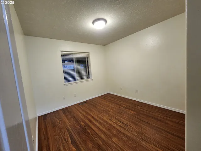 an empty room with a window and wooden floor