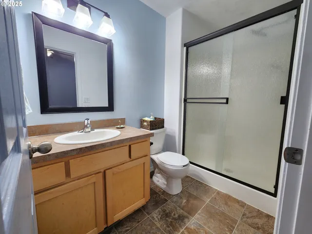 a bathroom with a granite countertop sink toilet and shower a mirror