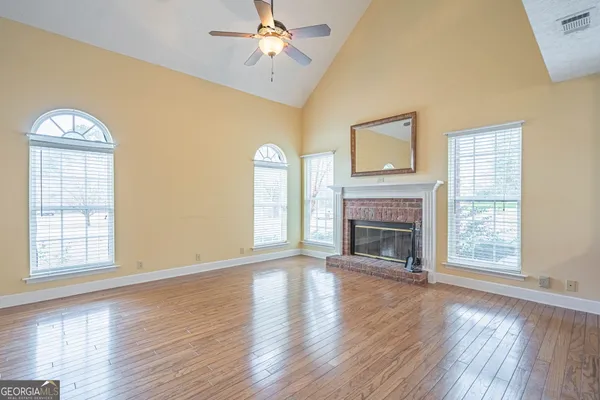 an empty room with windows fireplace and wooden floor