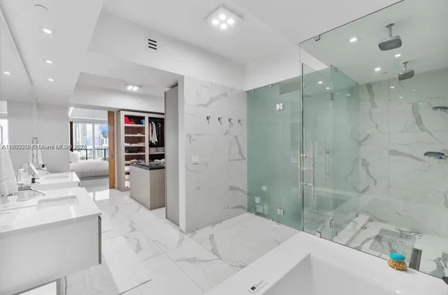 a large white kitchen with a sink stainless steel appliances and a window