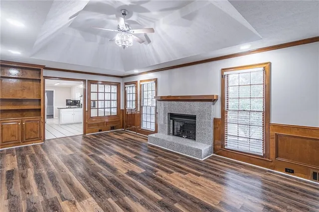 a view of an empty room with wooden floor fireplace and a window