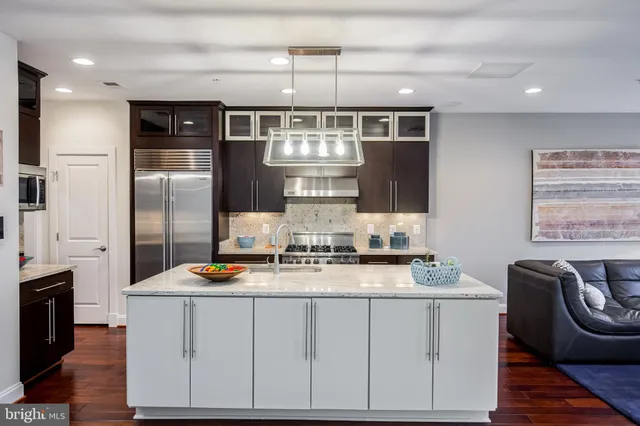 a kitchen with stainless steel appliances granite countertop a sink a stove a refrigerator cabinets and chairs