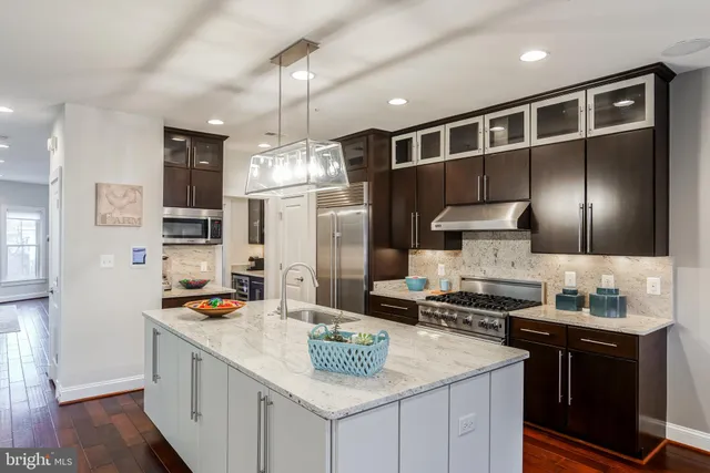 a kitchen with stainless steel appliances kitchen island granite countertop a sink stove and refrigerator