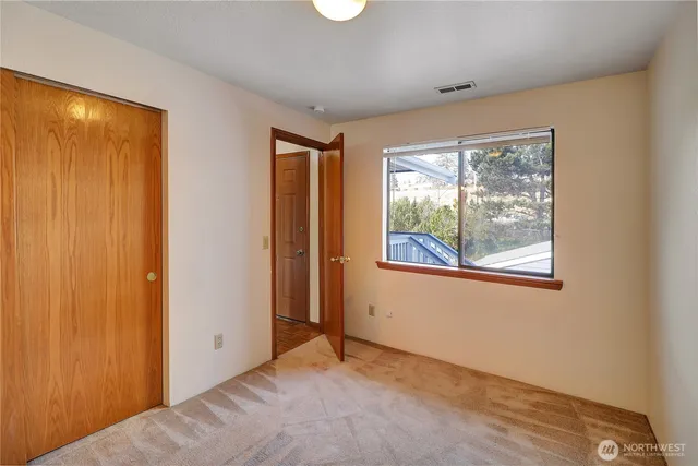 a view of an empty room with window and closet area