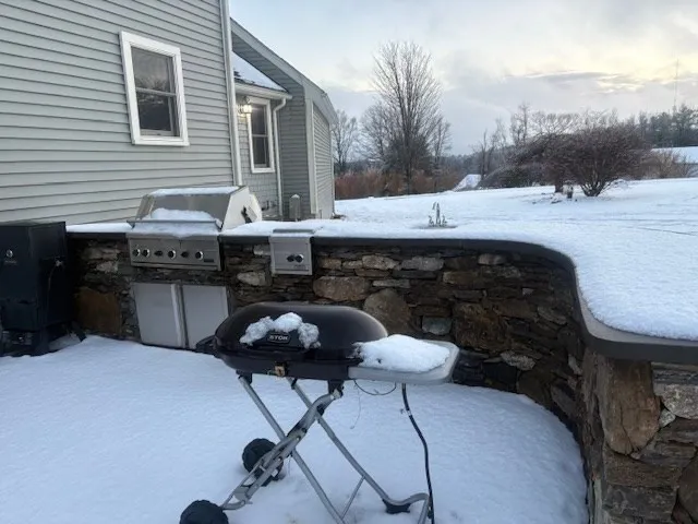 a backyard of a house with barbeque oven and outdoor seating