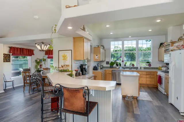 a very nice looking dining room with kitchen island furniture a large window and stainless steel appliances