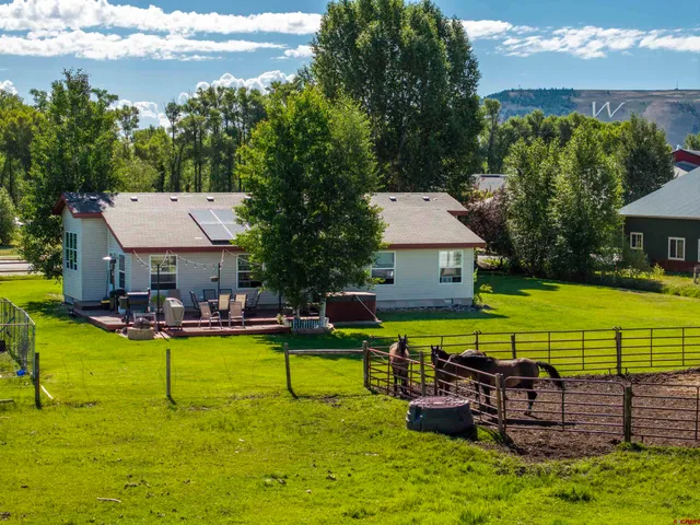 a view of a house with swimming pool lawn chairs and a yard
