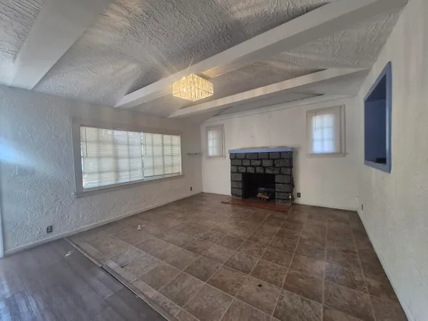 a view of an empty room with a fireplace and a window