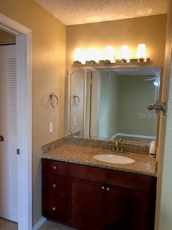 a bathroom with a granite countertop sink and mirror