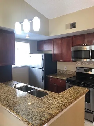 a kitchen with stainless steel appliances granite countertop a sink stove and refrigerator