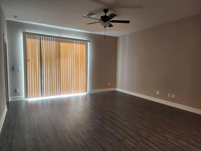 a view of an empty room with window and wooden floor