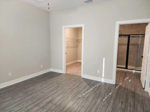 an empty room with wooden floor & closet and windows