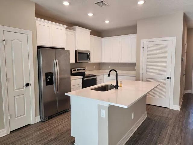 a kitchen with stainless steel appliances granite countertop a refrigerator a sink a stove a microwave and island with wooden floor