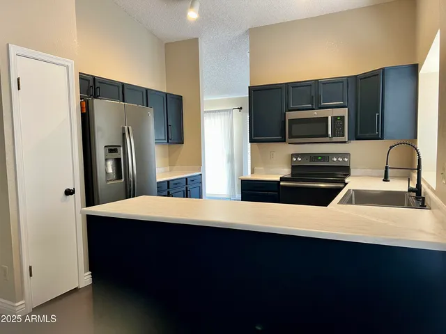 a kitchen with stainless steel appliances a sink dishwasher a refrigerator and white cabinets with wooden floor