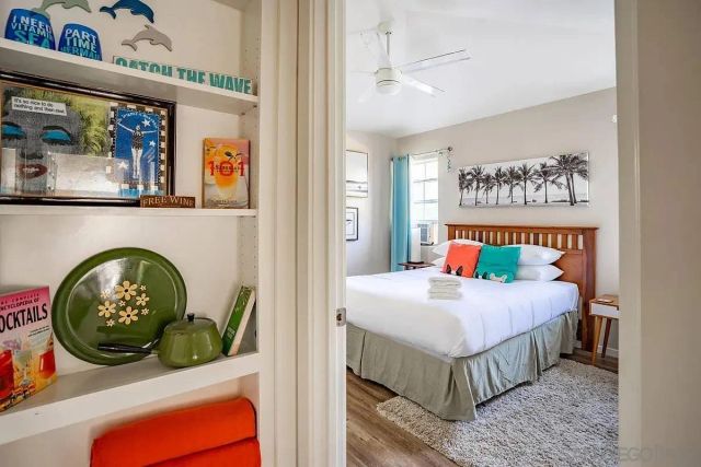 a bedroom with a bed a painting on the wall and a window