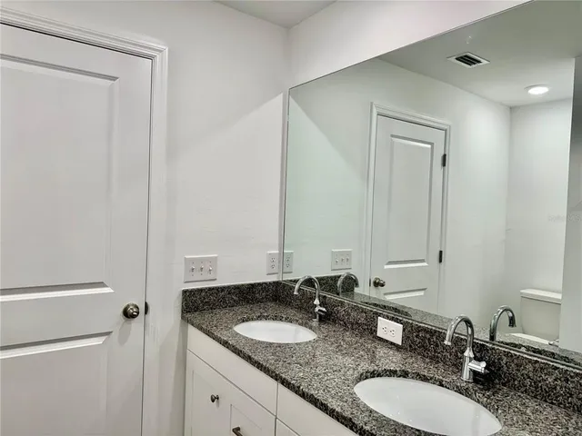 a bathroom with a granite countertop sink and a mirror