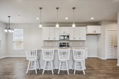 a kitchen with stainless steel appliances kitchen island granite countertop a dining table chairs and white cabinets