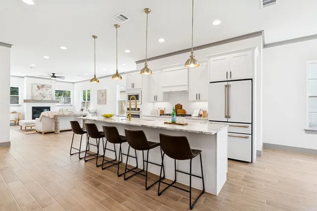 a kitchen with stainless steel appliances granite countertop a sink a stove a refrigerator and island with wooden floor