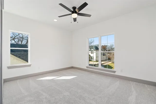 an empty room with windows and fan