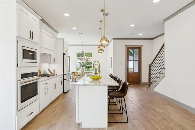 a kitchen with stainless steel appliances granite countertop a stove top oven a refrigerator a sink and a dining table with wooden floor