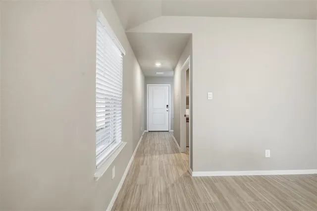 a view of a hallway with wooden floor and a bathroom