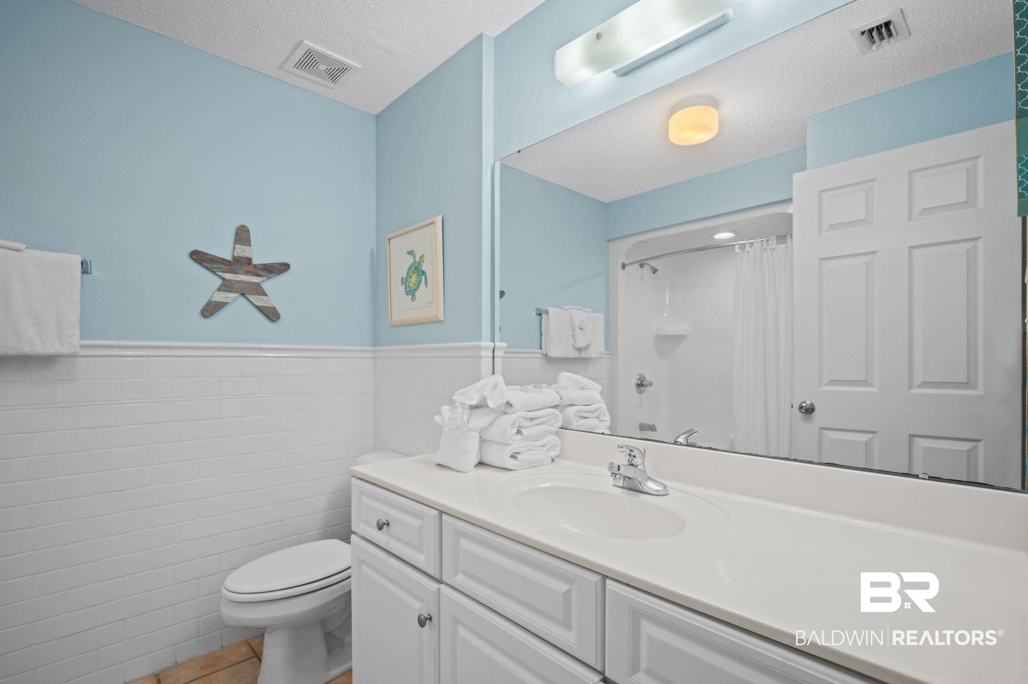 27580 Canal Road, Unit 1427 Orange Beach, AL 36561 - Photo 26 of 38 Bathroom featuring vanity, a shower with curtain, tile walls, a wainscoted wall, and a textured ceiling