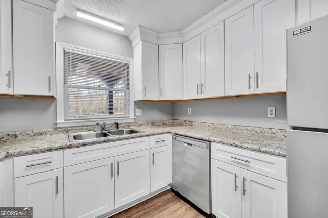 a kitchen with white cabinets white appliances and sink