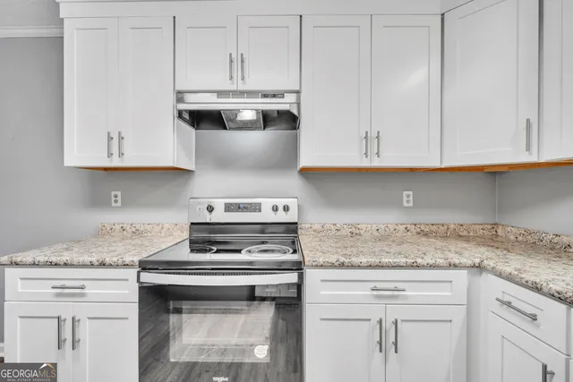 a kitchen with granite countertop white cabinets and a stove