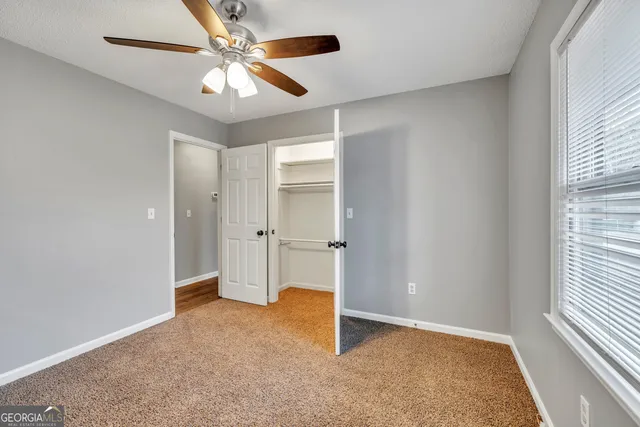 an empty room with windows and fan