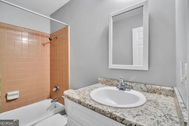 a bathroom with a granite countertop sink a mirror and a bathtub