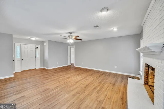 a view of an empty room with wooden floor and a fireplace