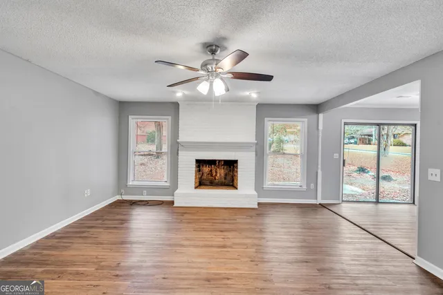 a view of an empty room with window and wooden floor