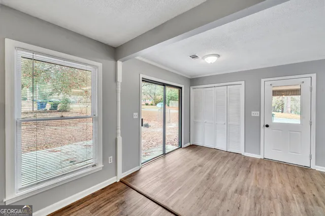 a view of an empty room with wooden floor and a window