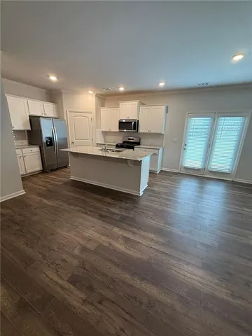 a large white kitchen with kitchen island a sink a stove a refrigerator and a oven with white cabinets