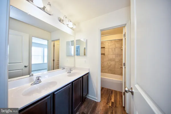 a bathroom with a double vanity sink a mirror and a bathtub
