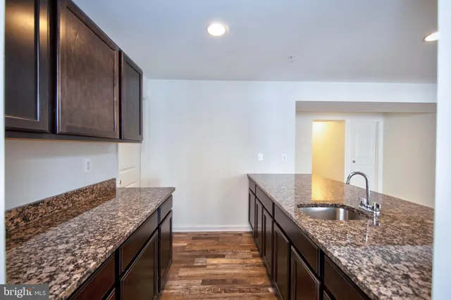 a kitchen with granite countertop kitchen island stainless steel appliances a sink stove and cabinets