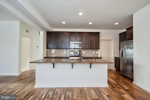 a large kitchen with stainless steel appliances kitchen island granite countertop wooden cabinets and a granite counter top
