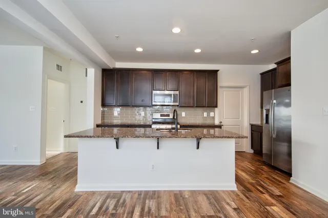 a large kitchen with stainless steel appliances kitchen island granite countertop wooden cabinets and a granite counter top