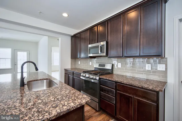 a kitchen with stainless steel appliances granite countertop a stove a sink dishwasher and wooden cabinets with a granite countertops