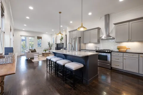 a kitchen with stainless steel appliances granite countertop a stove a sink dishwasher and a dining table with wooden floor