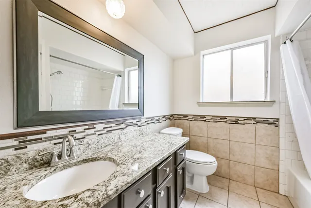 a bathroom with a granite countertop sink a toilet and a mirror