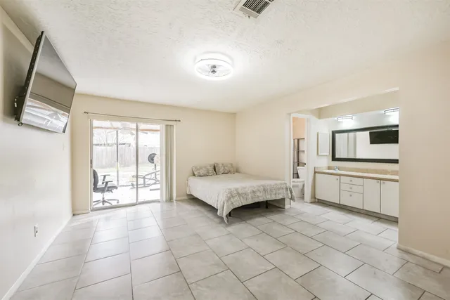 a spacious bedroom with a bed and flat screen tv