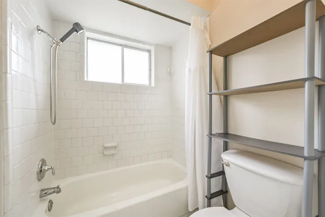 a bathroom with a tub toilet and window