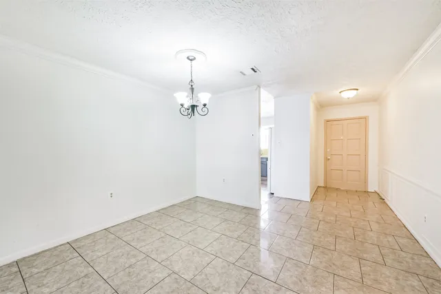a view of a room with a refrigerator and chandelier