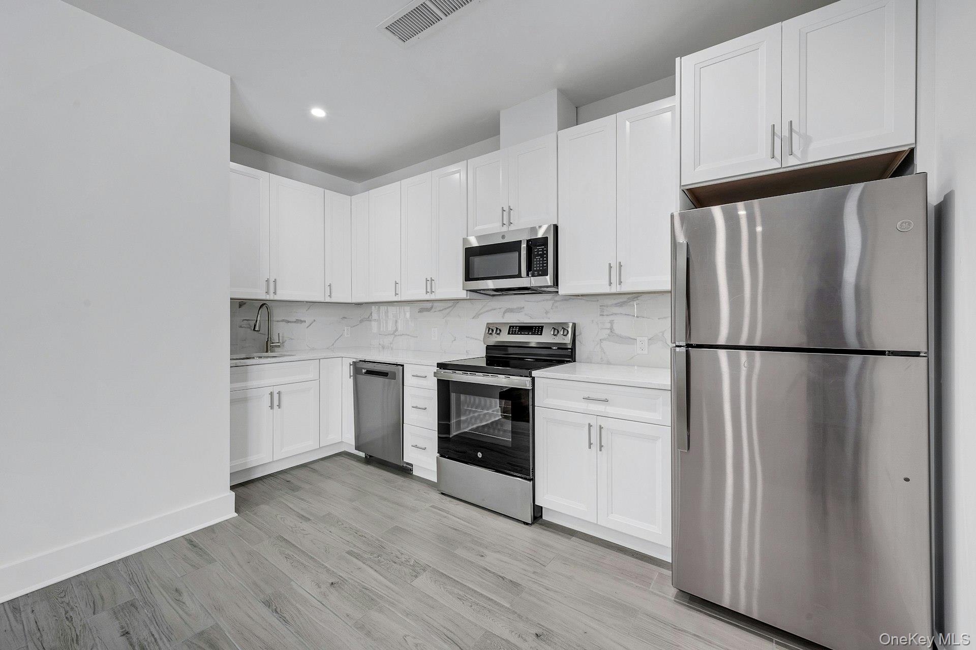 291 Main Street, Unit 1C Eastchester, NY 10709 - Photo 2 of 14 a kitchen with a refrigerator stove and white cabinets