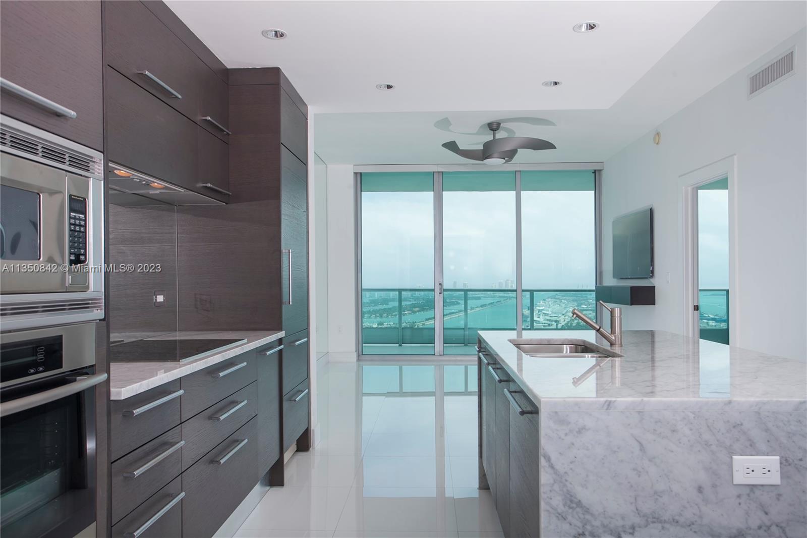 900 Biscayne Boulevard, Unit 4804 Miami, FL 33132 - Photo 8 of 17 a kitchen with granite countertop a sink and a refrigerator