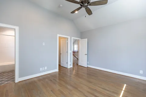 an empty room with wooden floor cabinet and windows