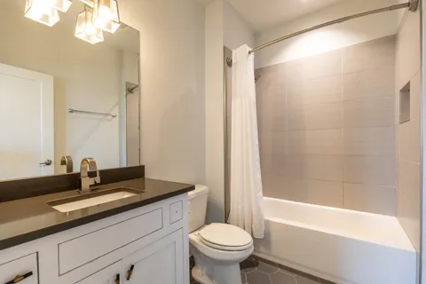 a bathroom with a granite countertop sink a toilet and a bathtub