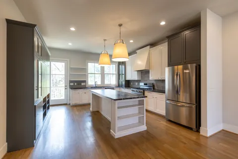a kitchen with stainless steel appliances granite countertop a refrigerator a sink dishwasher a stove and a refrigerator with wooden floor