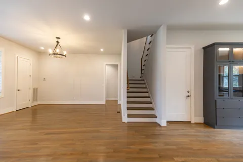 a view of an empty room with wooden floor and a ceiling fan